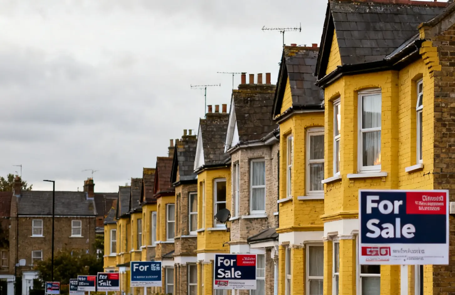 A street of yellow brick houses with for sale signs